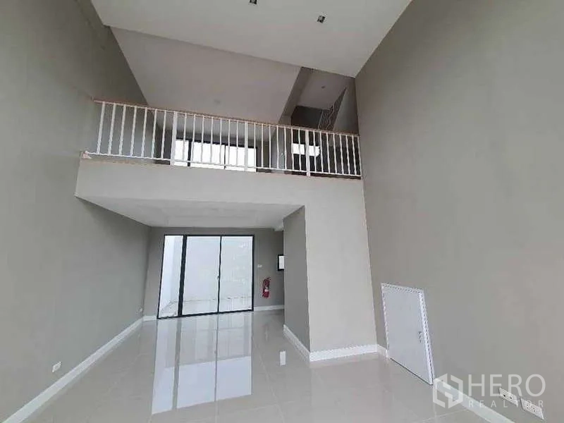 Home Office for rent in Lat Krabang, Bangkok - Double-height workspace with mezzanine level, white railing and sliding glass doors.