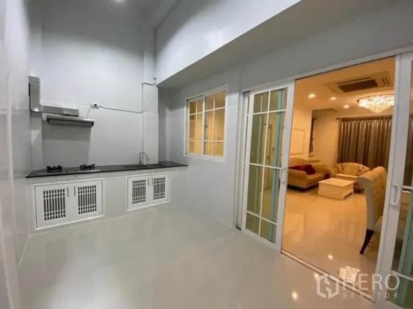 Townhouse for rent in Bang Na, Bangkok - Kitchen view opening to the living area through sliding glass doors.