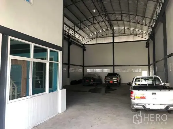 Warehouse for rent in Pak Kret, Nonthaburi - High-clearance warehouse bay with steel truss roof, internal office windows and open floor area.