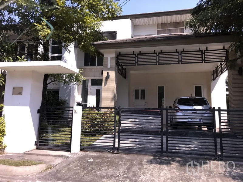 Detached House for sale in Saphan Sung, Bangkok - Two-storey detached house in Saphan Sung, Bangkok with gated driveway, covered two-car carport and an upper balcony shaded by trees.