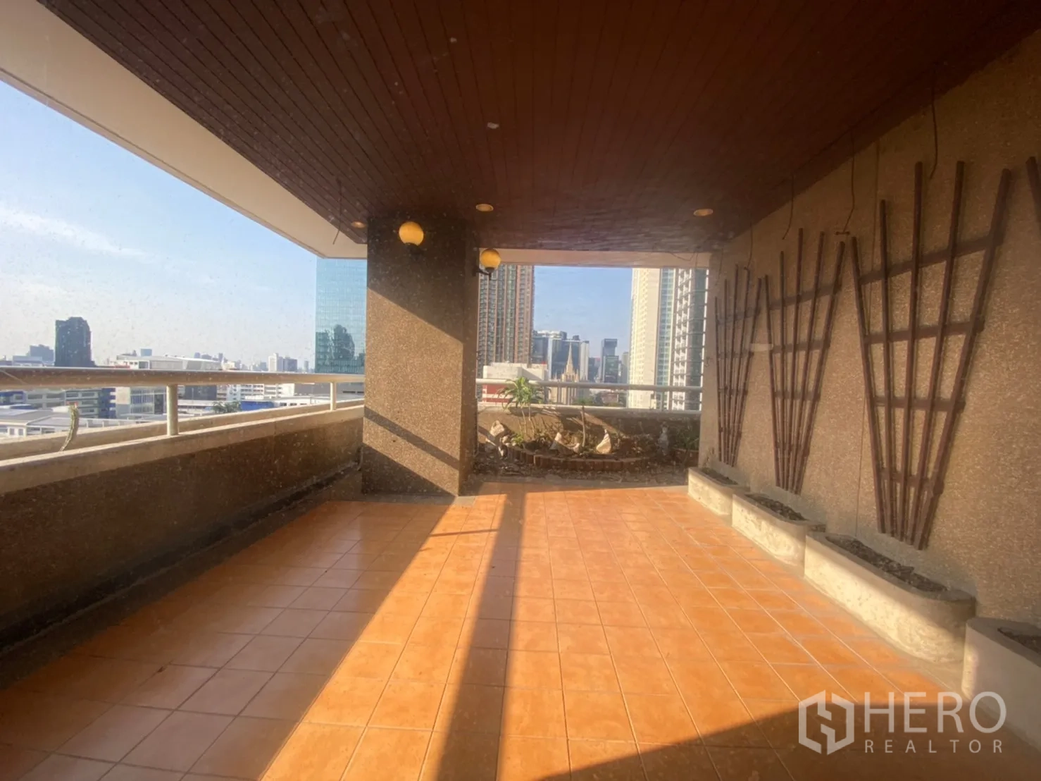 Condominium for rent or sale in Watthana, Bangkok - Covered terrace with terracotta tiles, planters and panoramic Asoke city view.