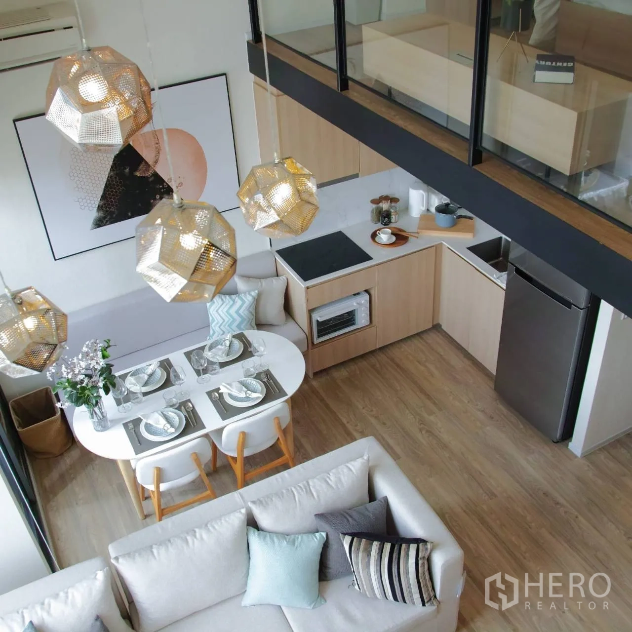 Condominium for rent or sale in Khlong Toei, Bangkok - Open-plan kitchen and dining with L-shaped counters, cooktop, fridge, and pendant lights.