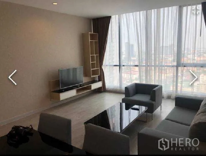Condominium for rent in Watthana, Bangkok - Living room with sofa set, TV console and floor-to-ceiling glazing overlooking Bangkok skyline.