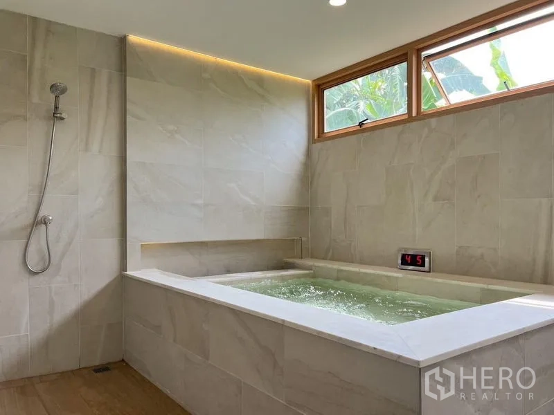 Townhouse for rent or sale - Hot soaking bath with temperature display beside high windows and a walk-in shower.