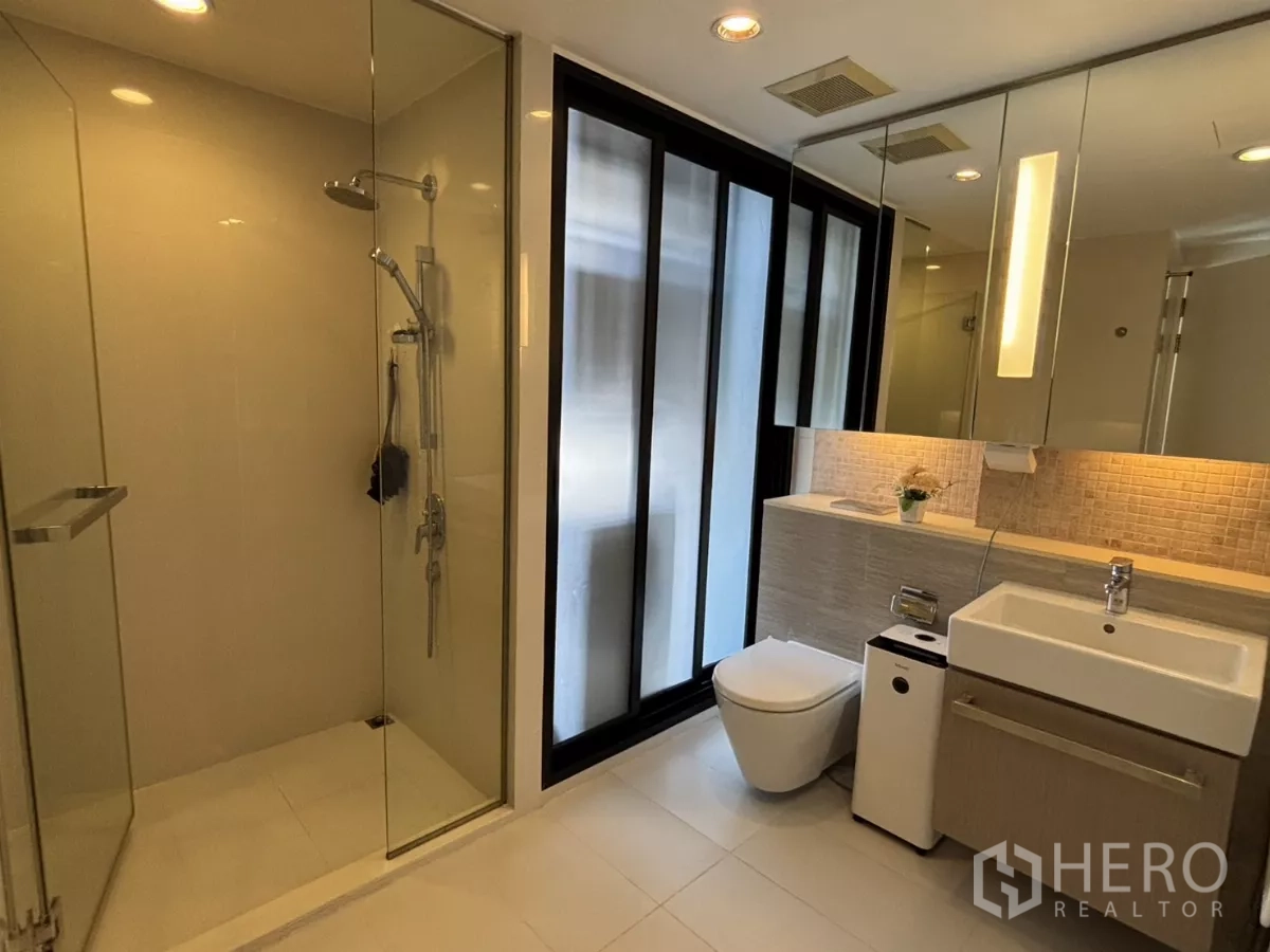 公寓 出售在Watthana, Bangkok - 现代浴室，玻璃淋浴间、洗手台与背光镜柜。