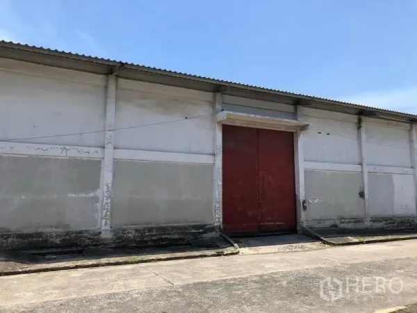 货栈 出租在Lat Krabang, Bangkok - 仓库立面特写，超大红色装卸门、混凝土坡道与波纹屋顶。