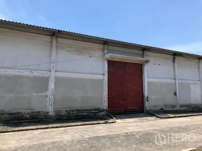 货栈 出租在Lat Krabang, Bangkok - 仓库立面特写，超大红色装卸门、混凝土坡道与波纹屋顶。
