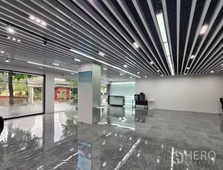 Showroom for rent in Bang Rak, Bangkok - Open-plan showroom interior with polished stone floors, floor-to-ceiling windows, and modern linear lighting.