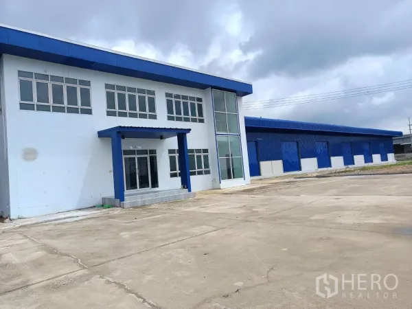 Warehouse for rent in Bang Len, Nakhon Pathom - Office building entrance beside long warehouse block on expansive paved yard.