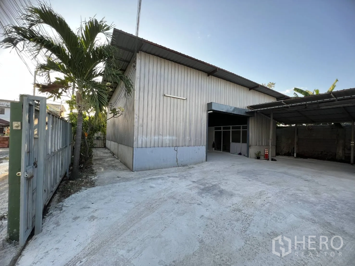 Warehouse for rent in Lat Krabang, Bangkok - Gated metal-clad warehouse exterior in Lat Krabang with wide driveway and covered parking.