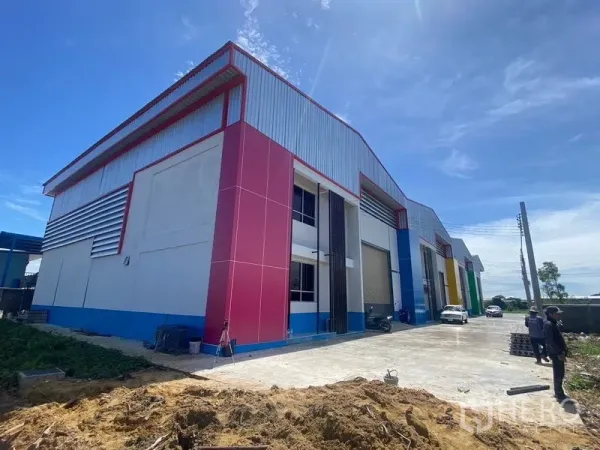 Warehouse for rent in Bang Phli, Samut Prakan - Contemporary warehouse exterior with wide driveway, roller shutter doors and parking area.