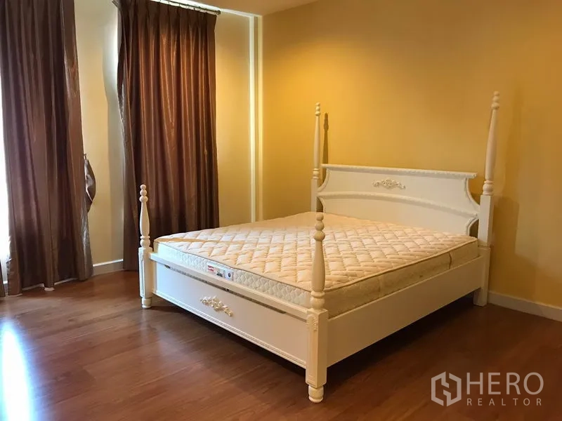 联排别墅 出租在Wang Thonglang, Bangkok - 主卧配白色四柱床，棕色窗帘与木地板。