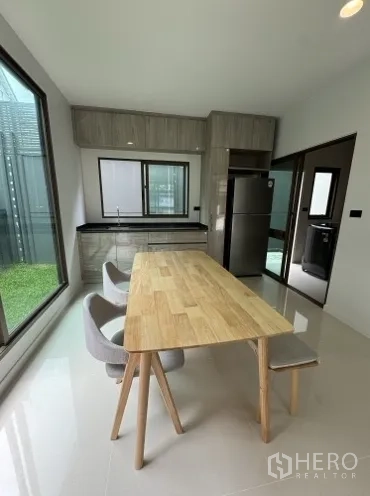 Detached House for rent in Bang Kapi, Bangkok - Light-filled kitchen with wooden dining table, cabinets and garden view.