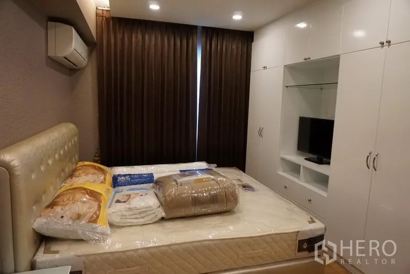 คอนโด ให้เช่าในWatthana, Bangkok - ห้องนอนอบอุ่น หัวเตียงบุผ้า ม่านทึบแสง และตู้บิวท์อินสีขาว