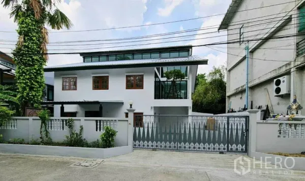 Home Office for rent in Lat Phrao, Bangkok - Street view of a renovated white home office with gated driveway and clerestory windows in Lat Phrao.