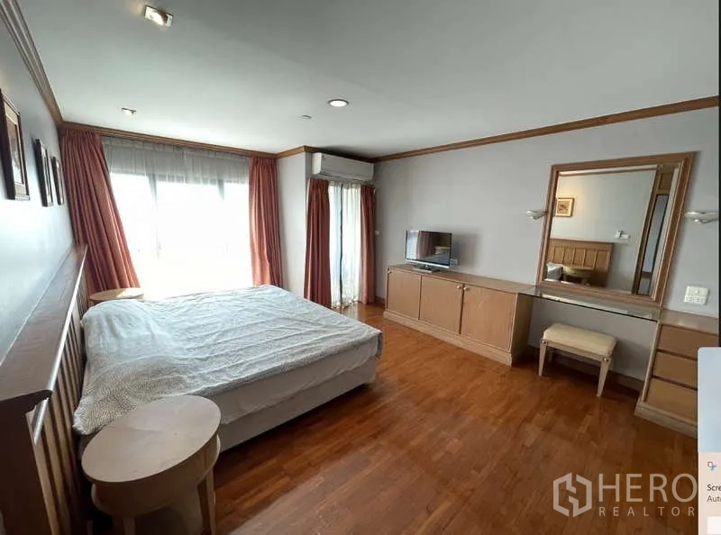 Condominium for rent - Bright bedroom with large window, curtains, wooden built-ins, vanity and a king-size bed.