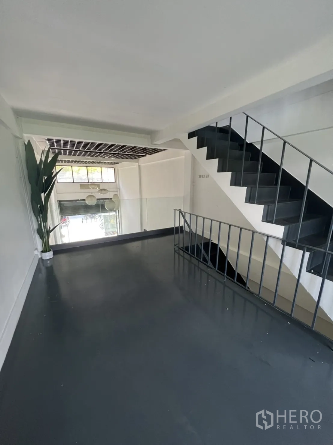 Shophouse for rent or sale in Watthana, Bangkok - Mezzanine level with metal staircase and railing overlooking the front hall.