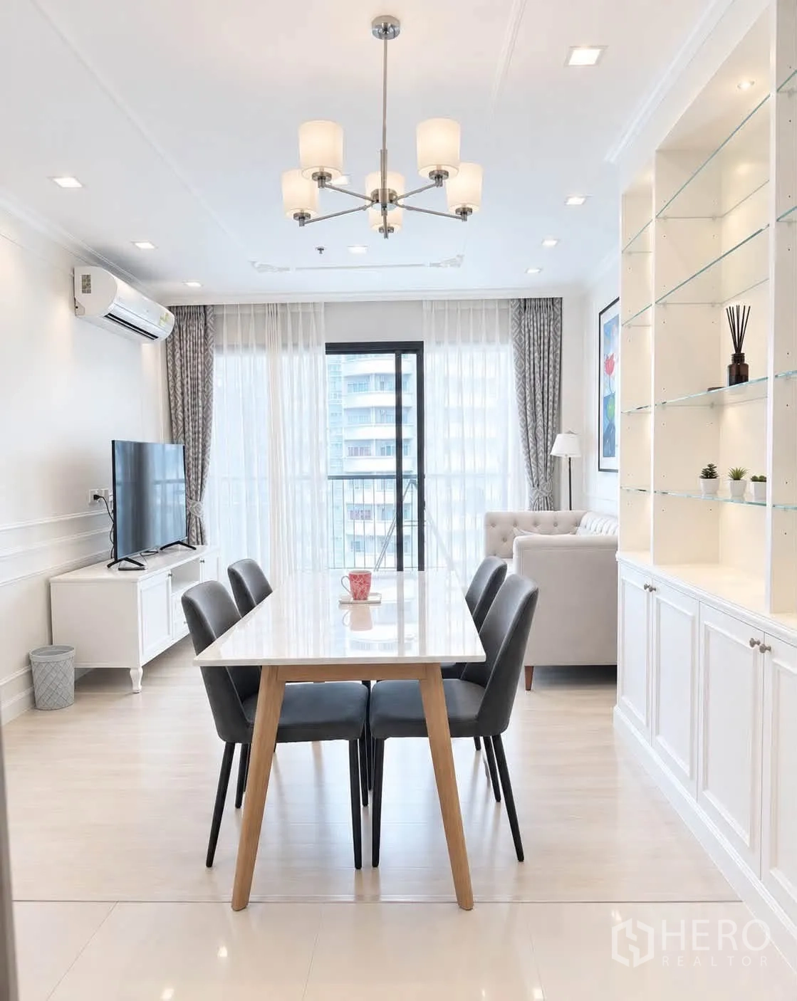 Condominium for rent in Pathum Wan, Bangkok - Dining area with white table, four chairs, chandelier, and display shelves.
