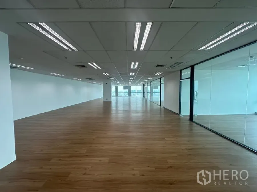 Office Space for rent - Deep floor plate office with timber-style flooring and reflective glass partitions facing city windows.