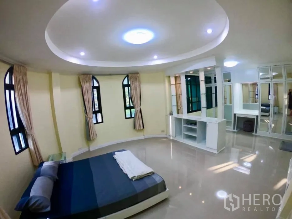 联排别墅 出租在Watthana, Bangkok - 转角卧室，圆形吊顶，拱形窗，带收纳柜和梳妆区。