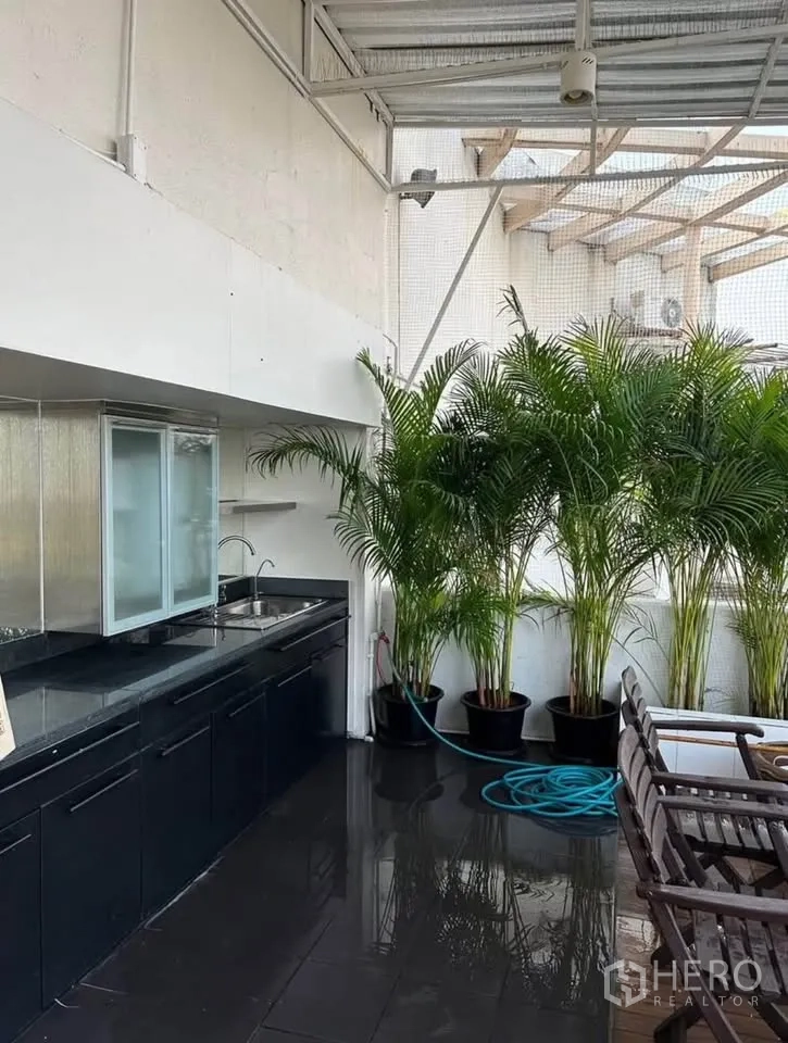 公寓 出租或出售在Yan Nawa, Bangkok - 覆盖式室外湿吧台，黑色台面与水槽，旁置棕榈绿植。
