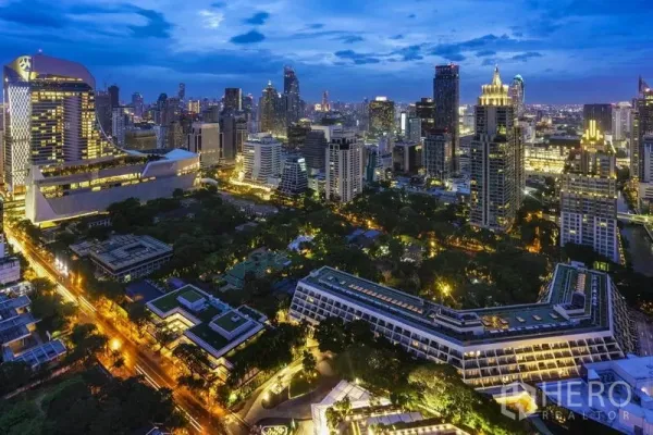 Condominium for sale in Pathum Wan, Bangkok - Evening skyline of Pathum Wan, Bangkok with illuminated towers and green park views near Phloen Chit.