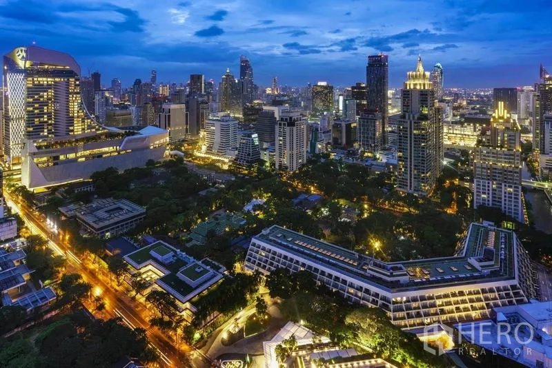 Condominium for sale in Pathum Wan, Bangkok - Evening skyline of Pathum Wan, Bangkok with illuminated towers and green park views near Phloen Chit.