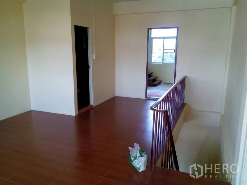 Shophouse for rent in Phra Khanong, Bangkok - Upper-floor landing with wooden handrail, doorway and glossy floor tiles.
