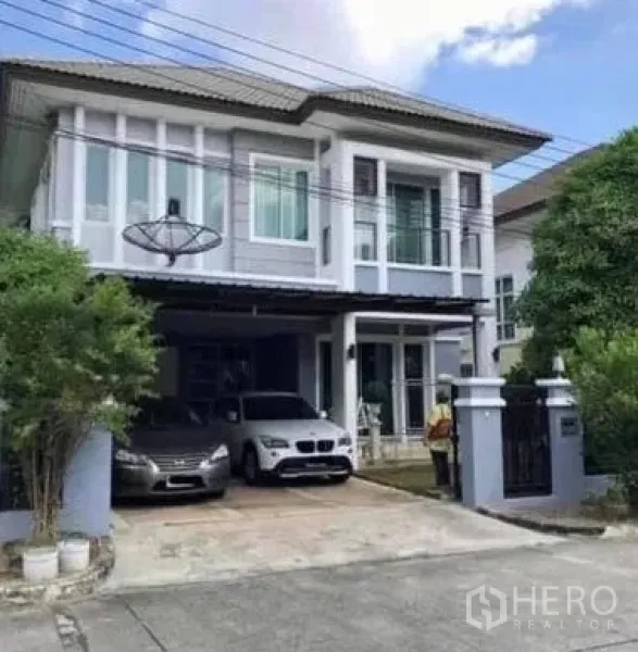 Detached House for sale in Khan Na Yao, Bangkok - Two-storey detached house exterior with gated driveway, covered carport for two cars, and balcony.