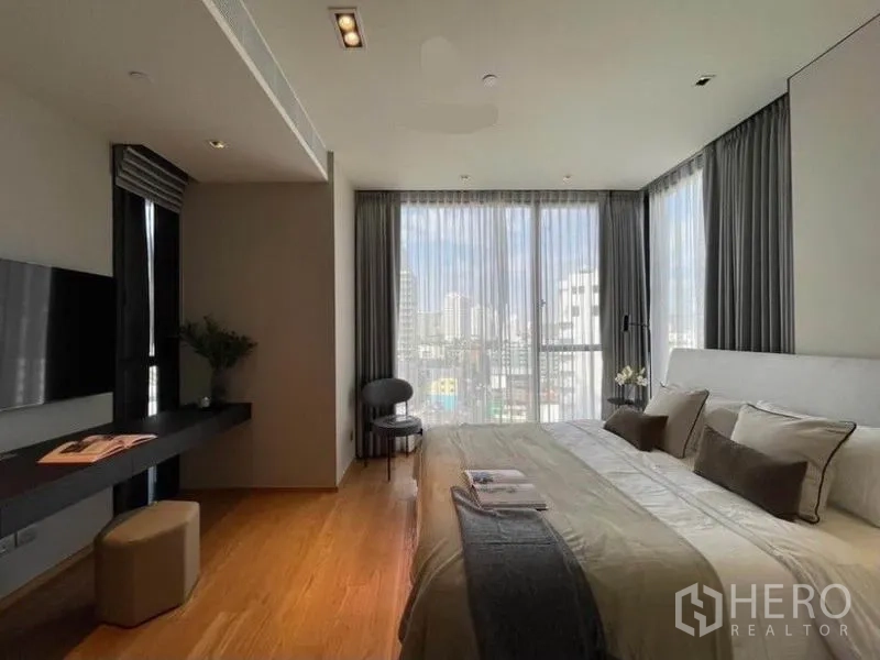 Condominium for rent in Khlong Toei, Bangkok - Spacious master bedroom with desk, panoramic windows and soft grey palette.
