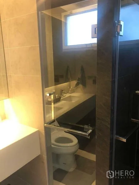 Detached House for rent or sale in Bang Kapi, Bangkok - Modern bathroom with a glass shower, toilet and vanity beside a window.