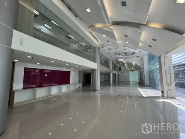 零售空间 出租在Huai Khwang, Bangkok - 挑高零售大厅，亮面地砖、整面落地玻璃与夹层。