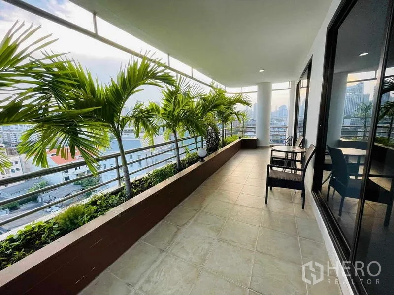 Condominium for rent - Long balcony lined with tropical plants overlooking Bangkok skyline.