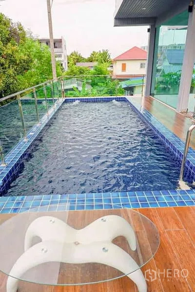独立式住宅 出售在Lat Phrao, Bangkok - 上层长形泳池，紧邻玻璃房与小圆桌。
