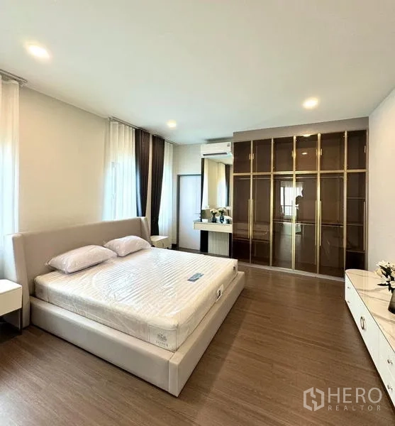 Detached House for rent or sale in Bang Phli, Samut Prakan - Primary bedroom with large glass-front wardrobe, dressing table, and king bed.