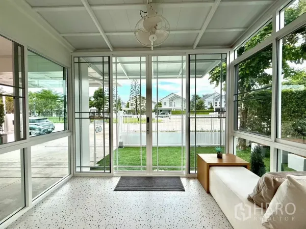 บ้าน ให้เช่าในBang Phli, Samut Prakan - ซันรูมกระจกมองออกสู่สนามหญ้าและถนนในโครงการ