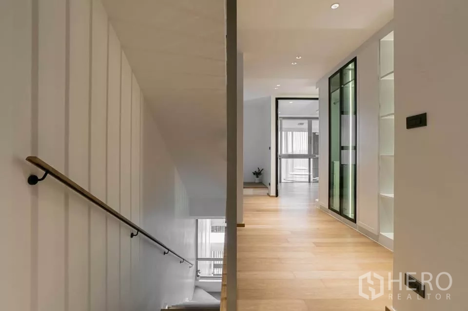 Townhouse for sale in Chatuchak, Bangkok - Bright hallway with wood floors and staircase leading to upper levels.