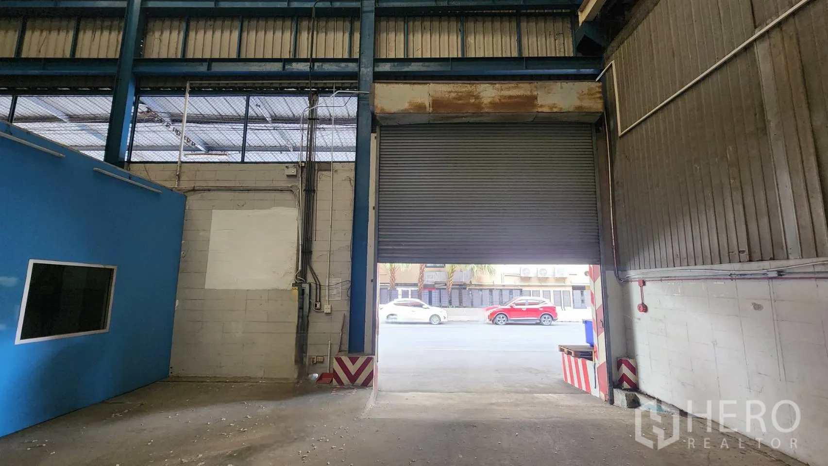 货栈 出租在Mueang Samut Prakan, Samut Prakan - 卷闸装卸门半开启，可通往仓库外的车道