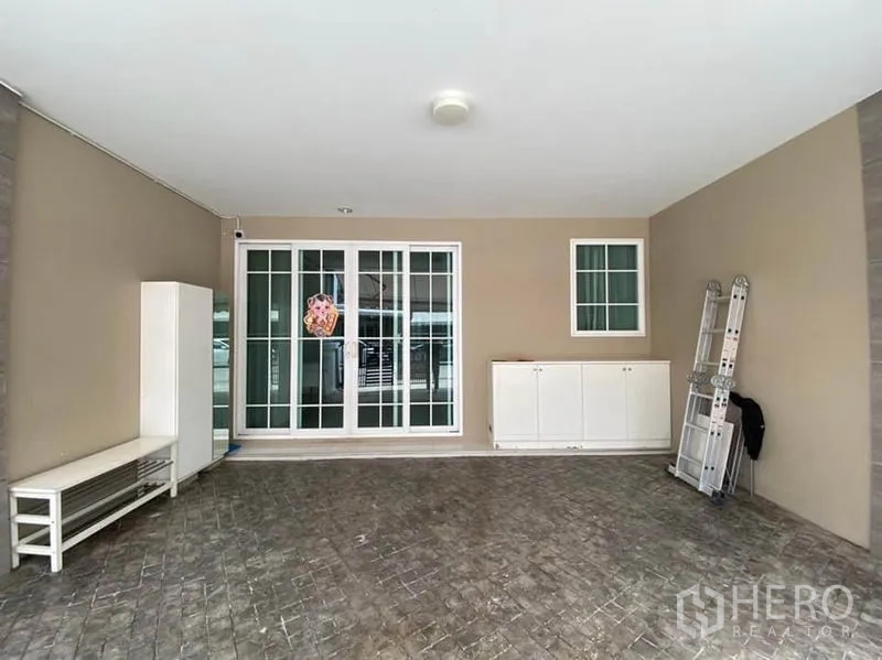 Townhouse for rent in Bang Na, Bangkok - Covered carport with sliding glass entrance and built‑in storage cabinets.