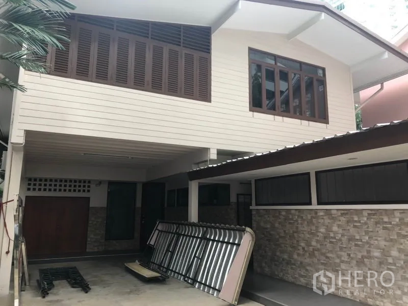 บ้าน ให้เช่าในWatthana, Bangkok - ด้านหน้าบ้านเดี่ยวสองชั้น มีที่จอดรถในร่ม บานเกล็ดไม้ และผนังลายหิน