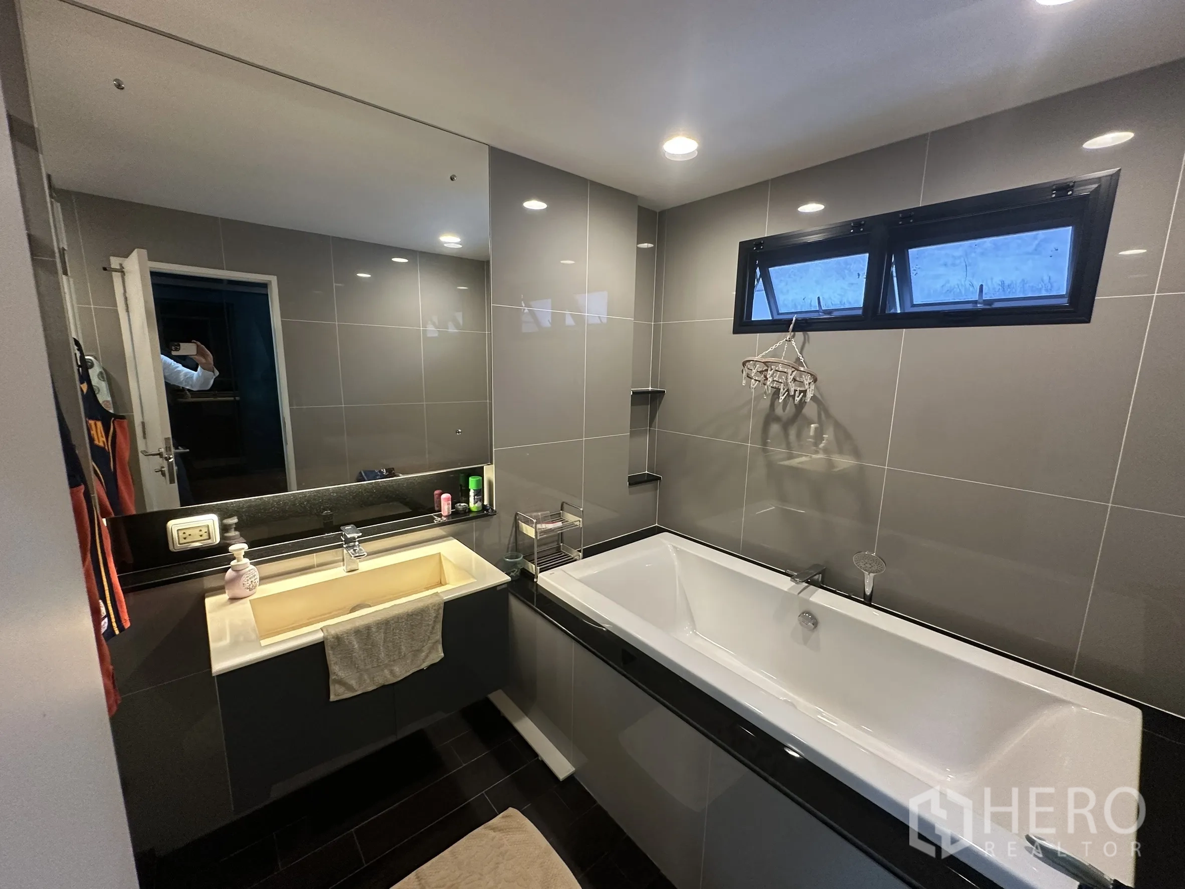 Detached House for rent in Lam Luk Ka, Pathum Thani - Grey-tiled bathroom with built-in tub and large mirror.