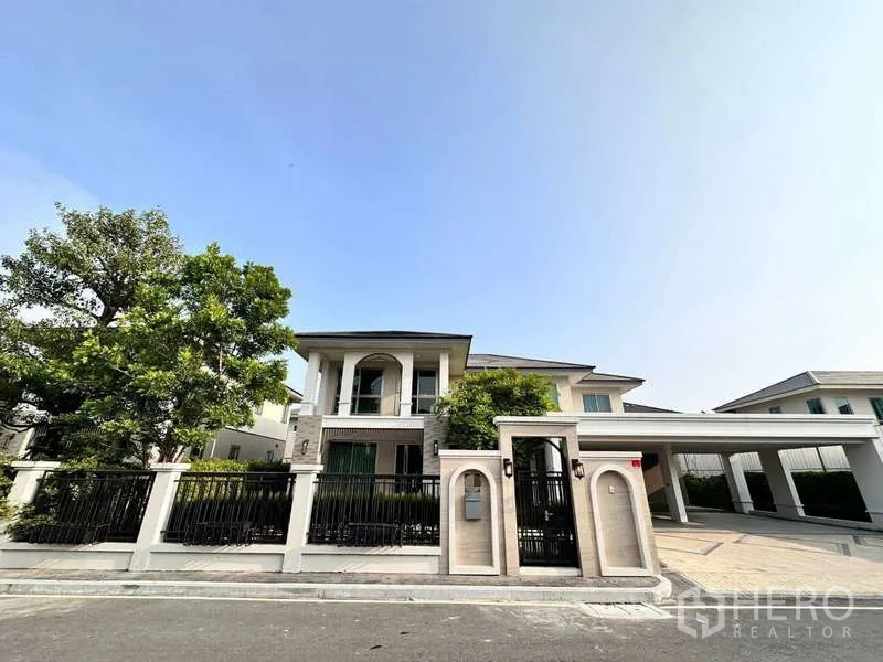 Detached House for rent or sale in Lat Krabang, Bangkok - Front elevation of the stylish house with secure gate and covered parking.