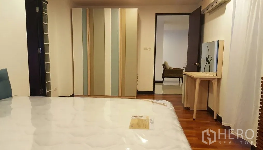 公寓 出租在Watthana, Bangkok - 卧室配木地板、条纹衣柜、梳妆台与空调。