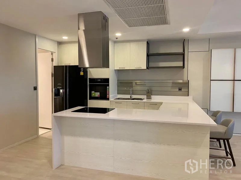 Condominium for rent in Khlong Luang, Pathum Thani - Contemporary island kitchen with induction hob, oven, range hood and double-door refrigerator.