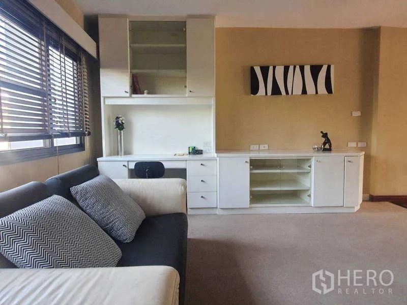 Townhouse for rent in Khlong Toei, Bangkok - Family room with sofa and white built-in cabinetry with desk.
