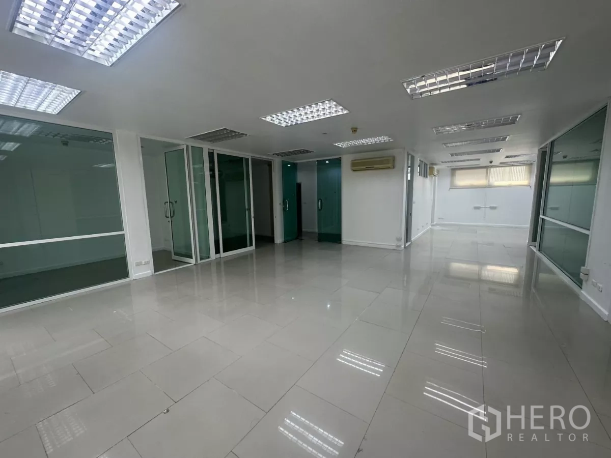 Office Space for rent in Huai Khwang, Bangkok - Open office space with multiple glass-walled rooms and bright fluorescent ceiling lights.