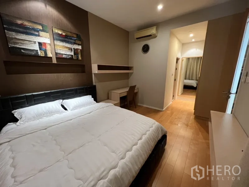 Condominium for rent in Chatuchak, Bangkok - Spacious bedroom view toward hallway, showing built-in shelf, study desk, and wood flooring.