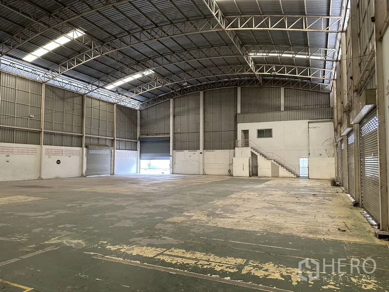 工厂 出租在Phra Nakhon Si Ayutthaya - 仓库内部空间高挑，拱形屋顶与钢桁架，装卸门和小型夹层办公室。