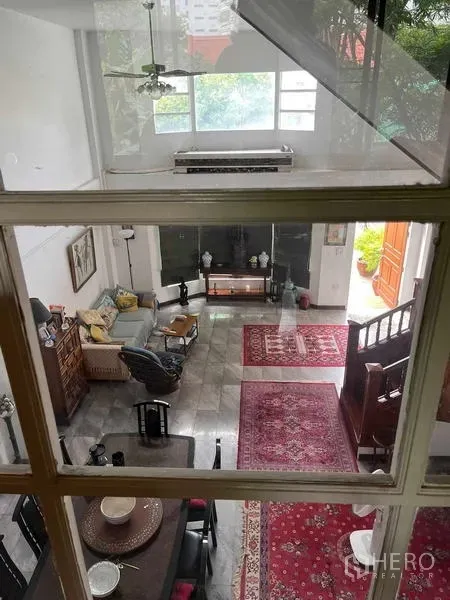 带办公室的家 出租在Bang Rak, Bangkok - 从夹层俯视挑高客厅，红色地毯与大窗户采光充足。