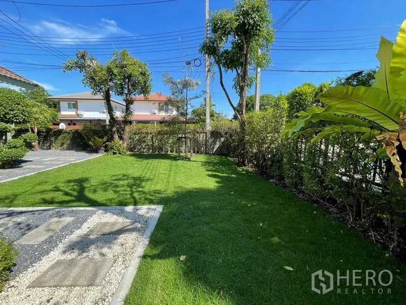 Detached House for sale in Lam Luk Ka, Pathum Thani - Landscaped lawn with stepping-stone path, trees and privacy hedges.